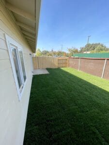A backyard with grass and a fence.